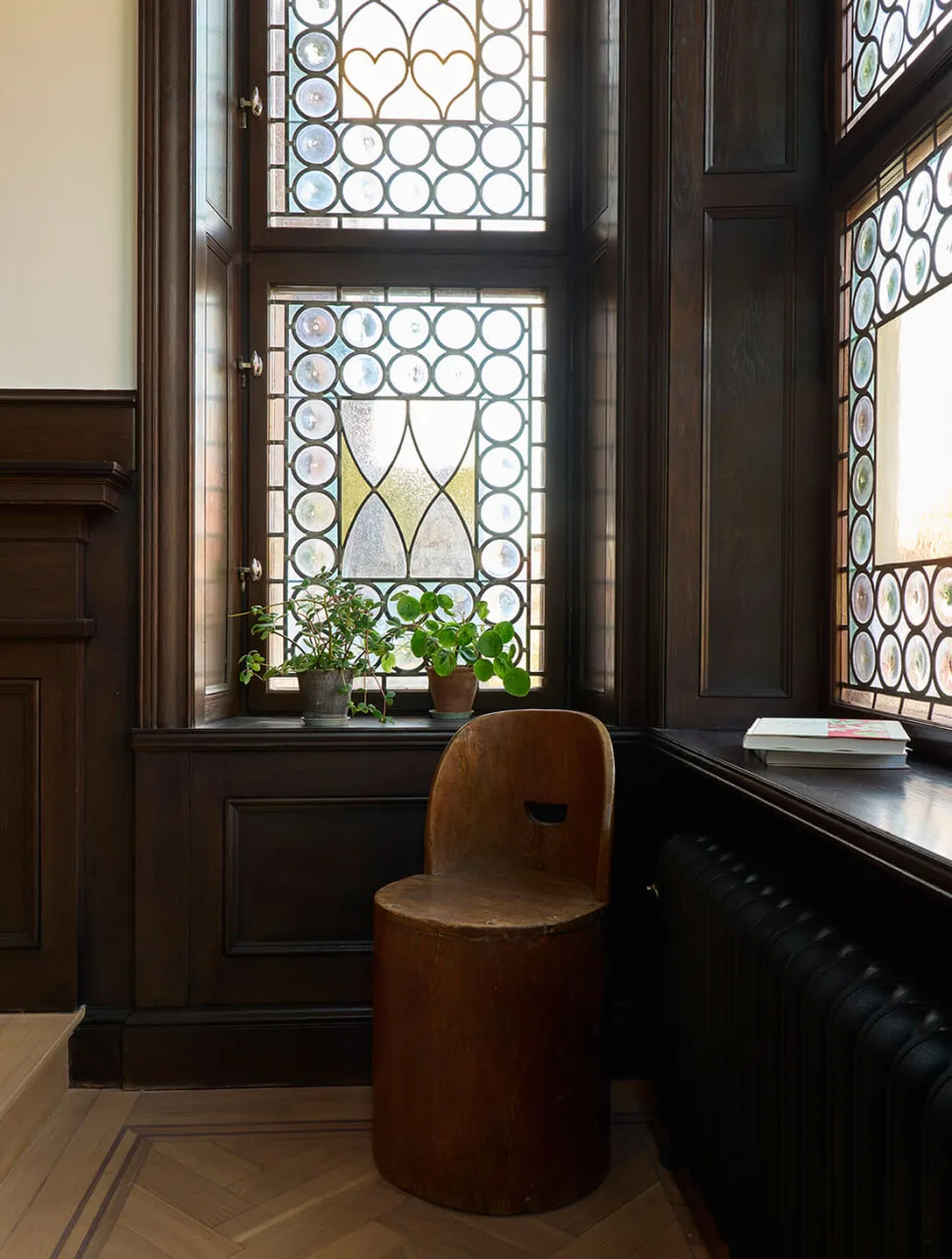 A stained-glass window and a carved wooden stool.