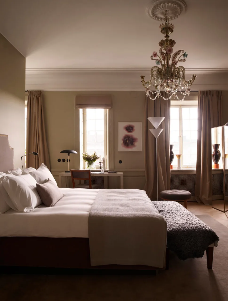A bedroom with a chandelier and tall windows.